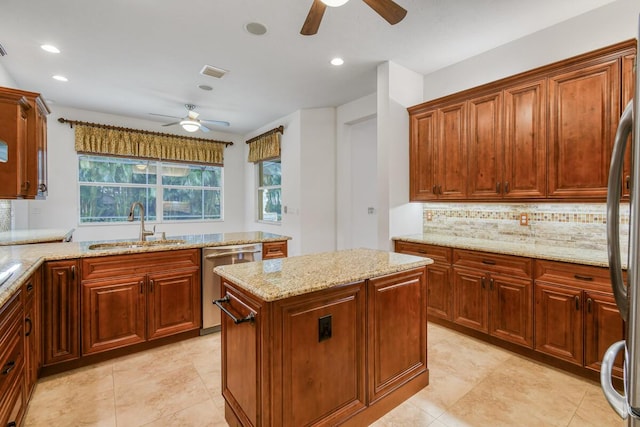 kitchen with light stone countertops, sink, a center island, stainless steel appliances, and decorative backsplash