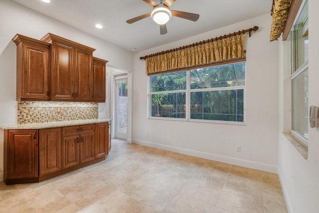 kitchen with decorative backsplash, light stone countertops, and ceiling fan