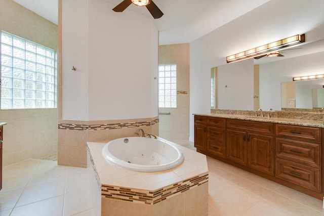 bathroom featuring tile patterned flooring, vanity, tiled bath, and a healthy amount of sunlight