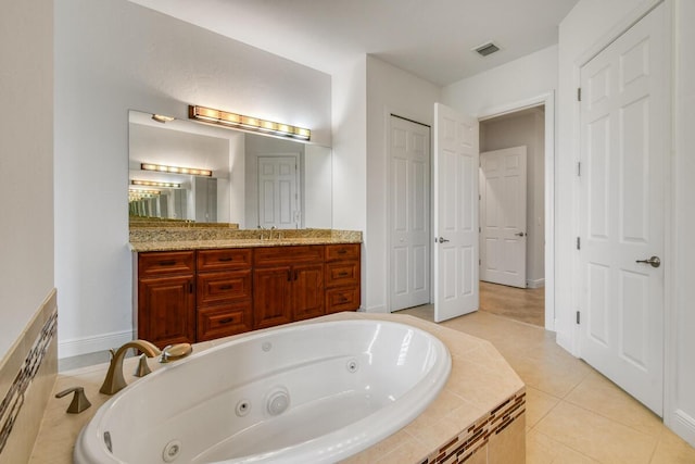 bathroom with tile patterned floors, vanity, and tiled tub