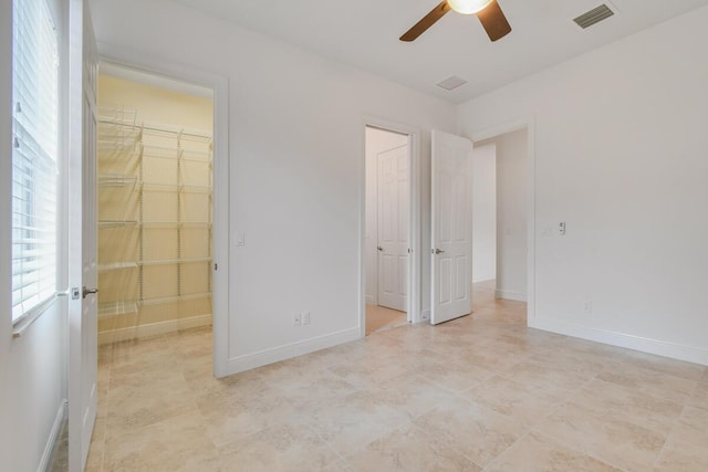 unfurnished bedroom with a closet, a spacious closet, and ceiling fan