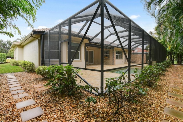 back of house featuring glass enclosure, ceiling fan, and a patio area