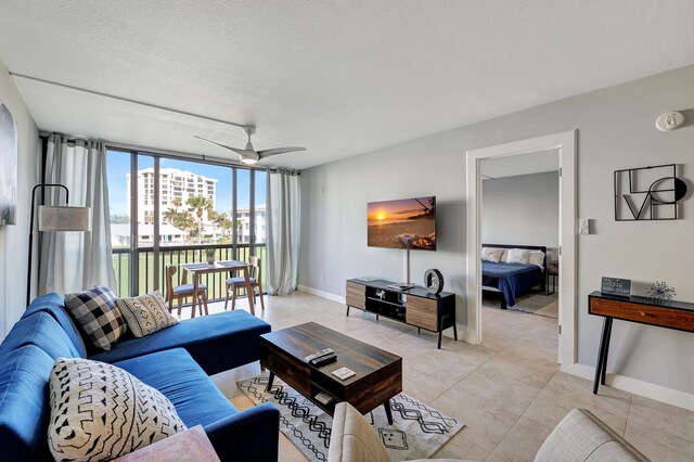 living room featuring ceiling fan, light tile patterned flooring, and a textured ceiling