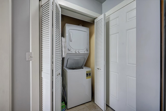 laundry room featuring stacked washer / drying machine and light tile patterned flooring