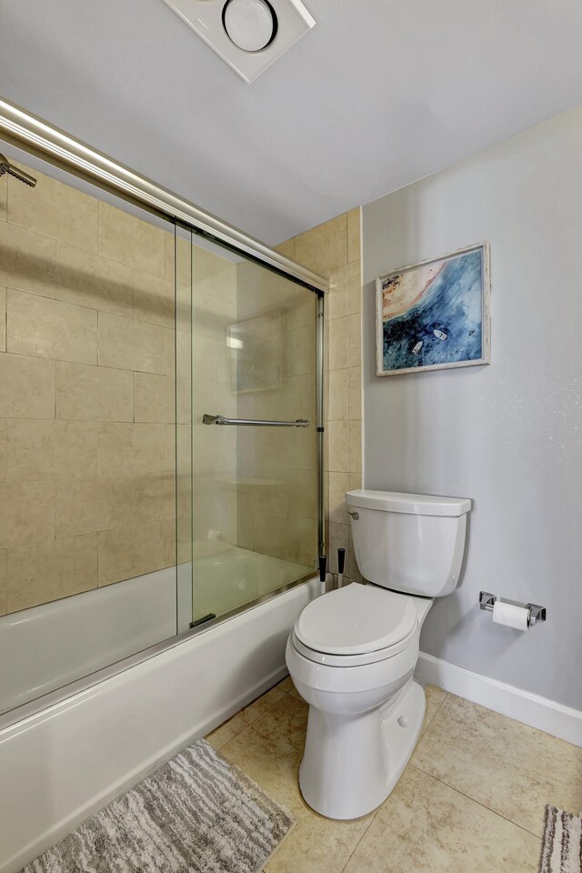 bathroom featuring tile patterned floors, toilet, and combined bath / shower with glass door