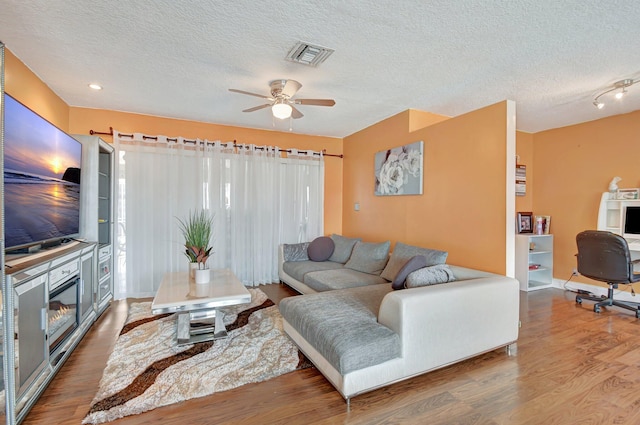 living room with a textured ceiling, hardwood / wood-style flooring, and ceiling fan