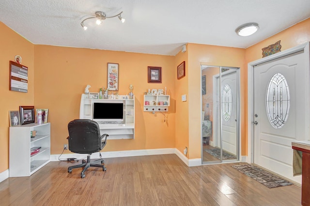 home office featuring a textured ceiling and light hardwood / wood-style flooring