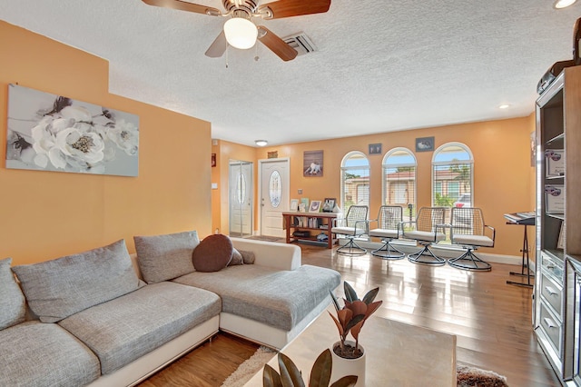 living room featuring ceiling fan, wood-type flooring, and a textured ceiling