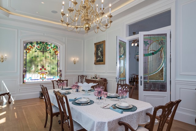 dining area featuring an inviting chandelier, light wood-type flooring, ornamental molding, and a tray ceiling