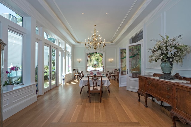 dining space with a notable chandelier, light wood-type flooring, ornamental molding, and a wealth of natural light