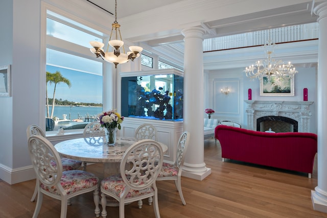 dining area with a notable chandelier, a water view, light wood-type flooring, and a fireplace