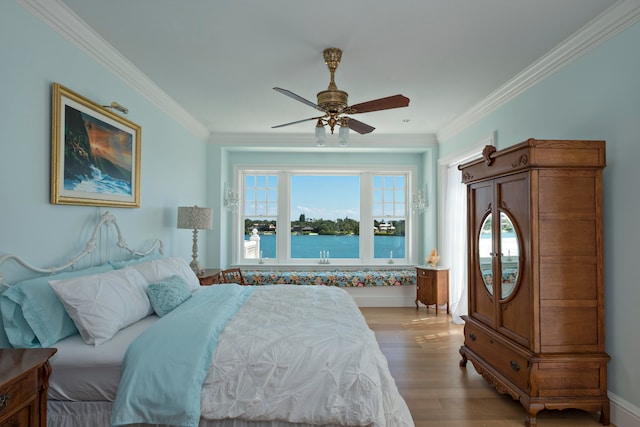 bedroom featuring ceiling fan, light hardwood / wood-style flooring, a water view, and ornamental molding