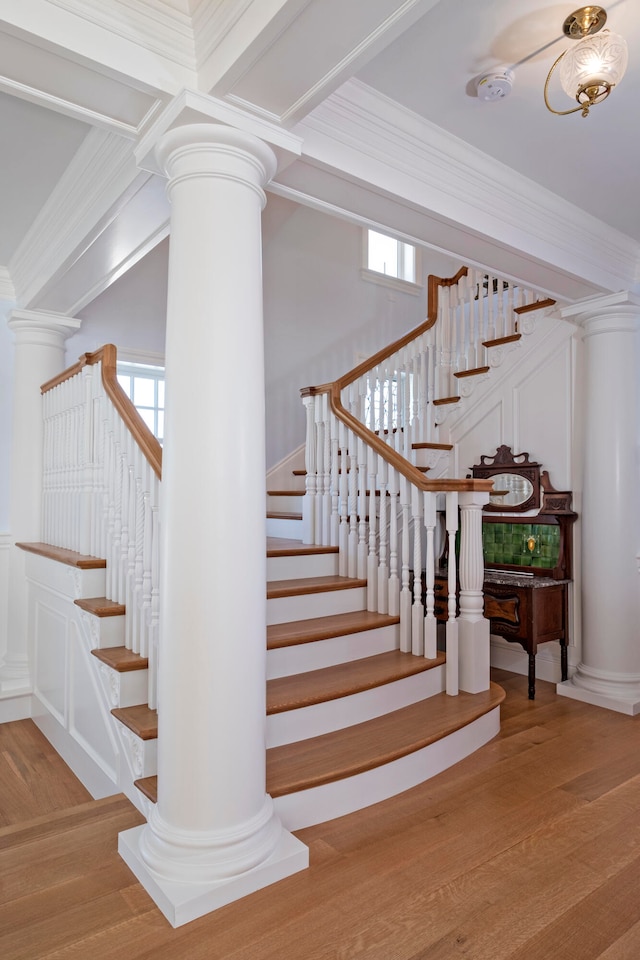 stairs featuring beamed ceiling, wood-type flooring, and crown molding