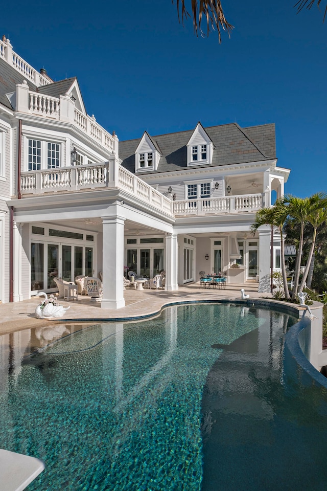 rear view of house featuring a balcony, a patio, and french doors