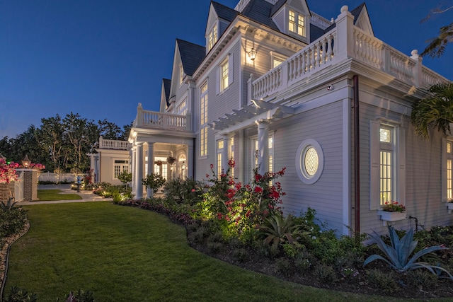 view of side of property with a lawn and a balcony