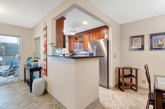 kitchen featuring kitchen peninsula, a textured ceiling, stainless steel refrigerator, and ceiling fan