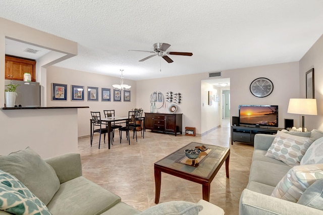 living room featuring a textured ceiling and ceiling fan with notable chandelier