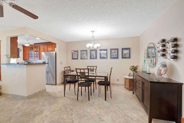 dining area with ceiling fan with notable chandelier and a textured ceiling