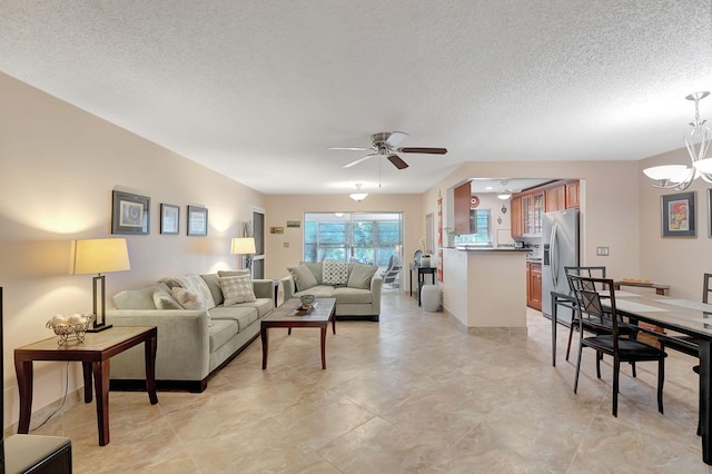 living room with ceiling fan with notable chandelier and a textured ceiling