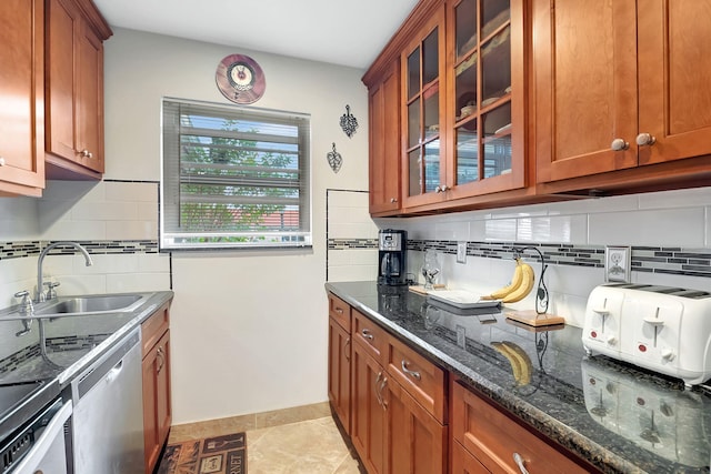 kitchen with sink, stainless steel dishwasher, dark stone countertops, decorative backsplash, and light tile patterned flooring