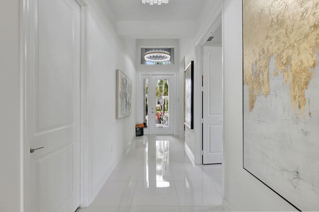 hall with light tile patterned floors and an inviting chandelier