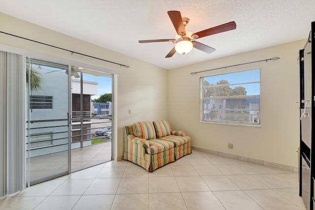 living area with ceiling fan, light tile patterned flooring, and a textured ceiling