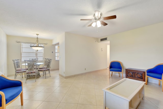 living area with ceiling fan, light tile patterned floors, and a textured ceiling