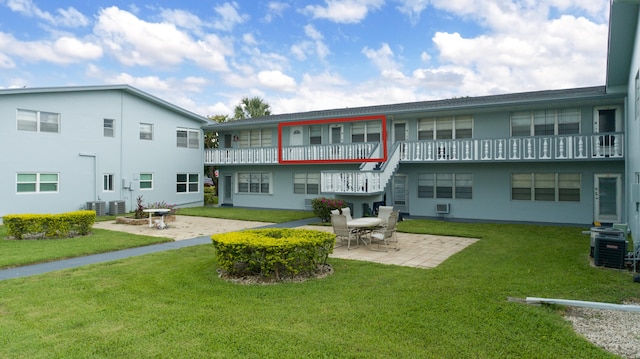 rear view of property featuring a lawn, cooling unit, and a patio