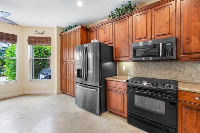 kitchen with decorative backsplash, a textured ceiling, stainless steel appliances, and light stone counters