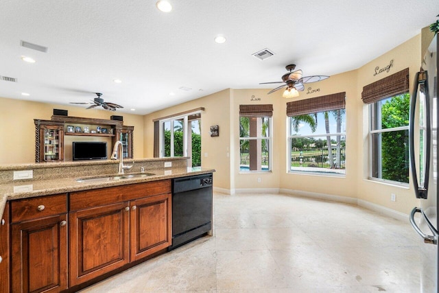 kitchen featuring stainless steel refrigerator, light stone countertops, dishwasher, and sink