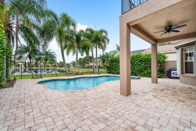 view of swimming pool with a patio, a water view, and ceiling fan