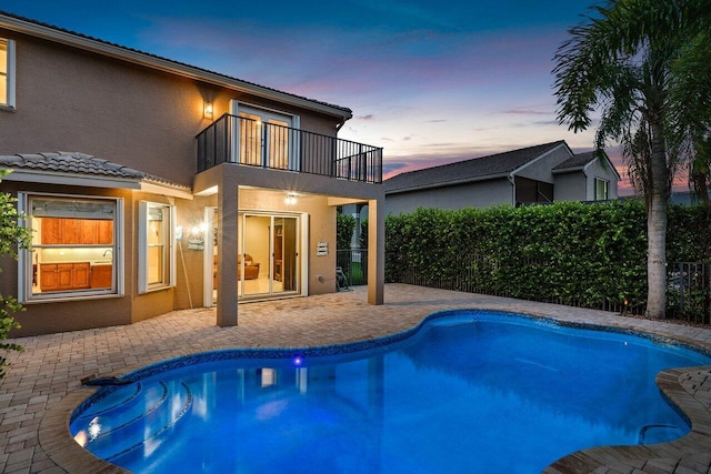 pool at dusk featuring a patio area