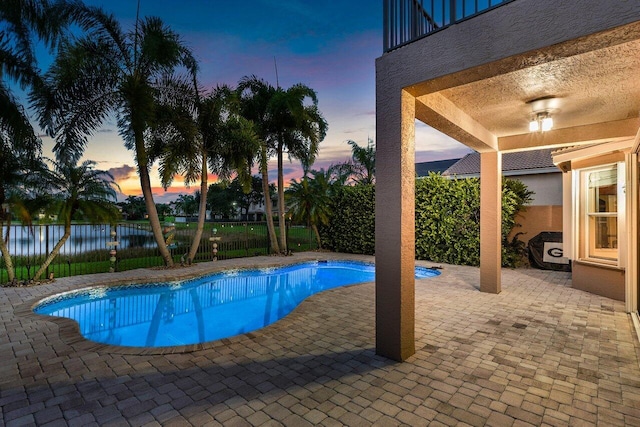 pool at dusk featuring a patio area