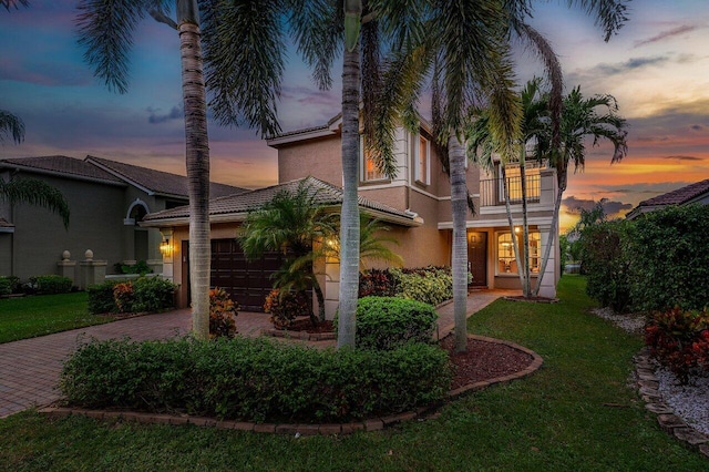 mediterranean / spanish-style home featuring a yard, a balcony, and a garage