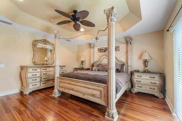 bedroom featuring hardwood / wood-style floors, ceiling fan, and a raised ceiling