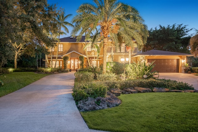 view of front of house featuring a front yard, a balcony, and a garage