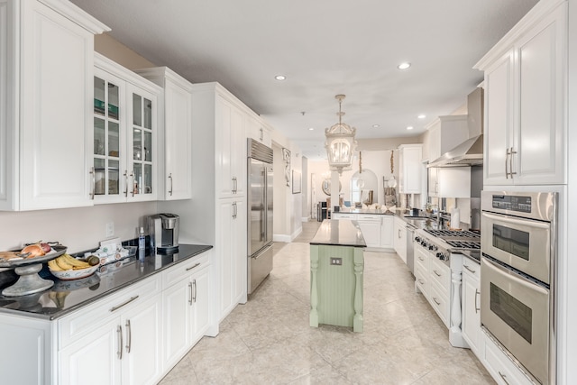 kitchen with white cabinets, light tile patterned floors, appliances with stainless steel finishes, decorative light fixtures, and a kitchen island