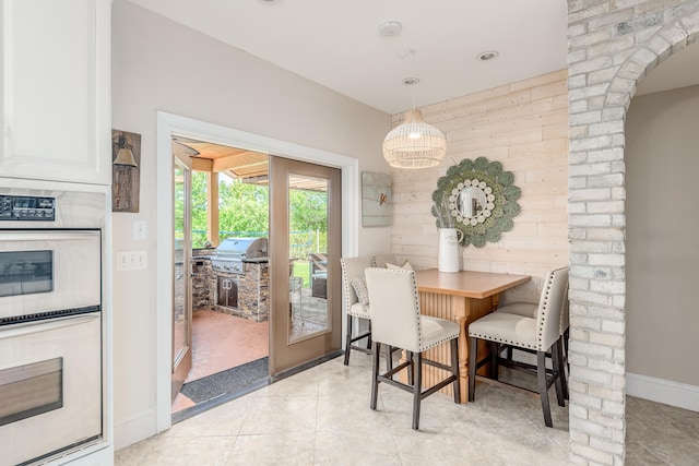 dining space featuring light tile patterned flooring and wooden walls