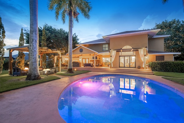 pool at dusk with ceiling fan, a pergola, a patio, and french doors