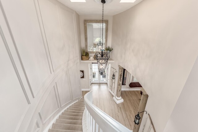 staircase featuring hardwood / wood-style flooring, a notable chandelier, a skylight, and french doors