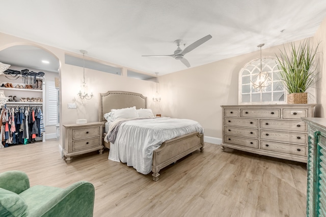 bedroom with ceiling fan with notable chandelier, light hardwood / wood-style floors, and a closet