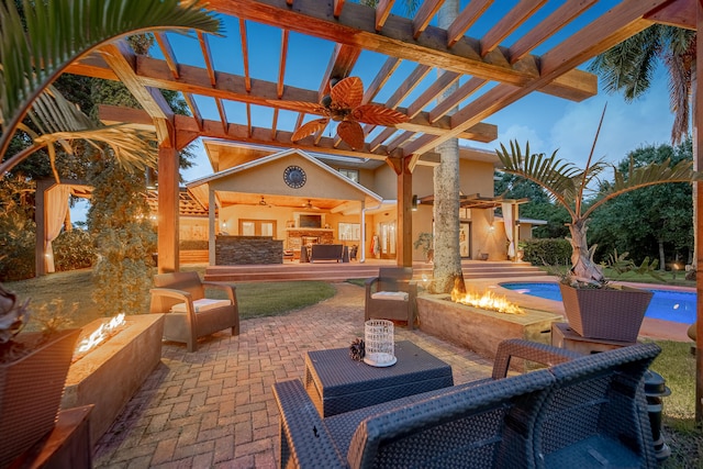 patio terrace at dusk featuring a pergola, an outdoor fire pit, and ceiling fan