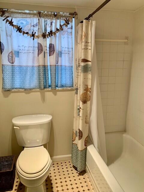 bathroom with toilet and shower / bath combo with shower curtain