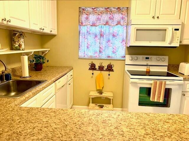 kitchen featuring white cabinets, white appliances, light stone counters, and sink