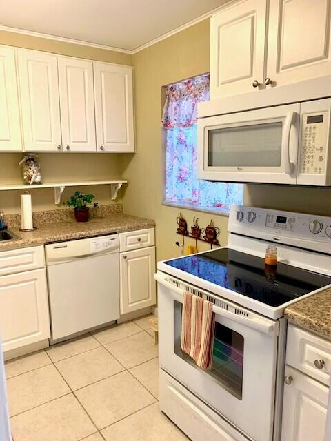 kitchen with white appliances, white cabinets, sink, crown molding, and light tile patterned flooring