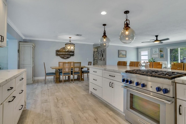 kitchen featuring white cabinets, light stone counters, high end range, decorative light fixtures, and crown molding