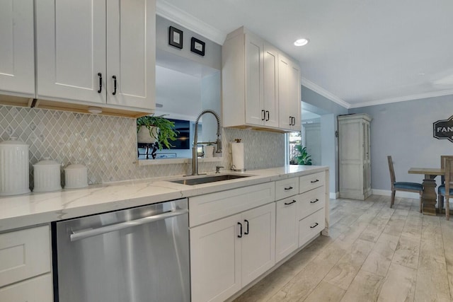 kitchen with stainless steel dishwasher, ornamental molding, white cabinetry, a sink, and light stone countertops