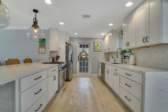 kitchen featuring visible vents, stainless steel appliances, a kitchen bar, white cabinetry, and a sink