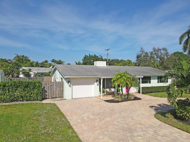 view of front facade with a garage, fence, decorative driveway, a front lawn, and stucco siding