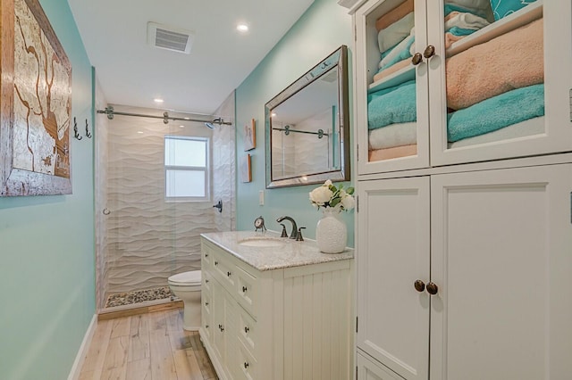 bathroom featuring visible vents, toilet, a stall shower, vanity, and wood finished floors